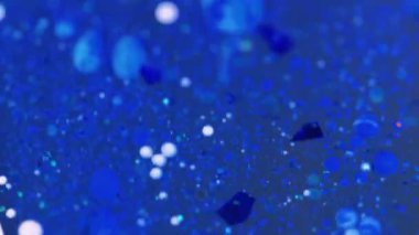 Sıvı sim damlası. Yağ sıvısı. Odaklanmamış mavi renk parçacıkları parıldayan boya damlaları pigment su mürekkebi emülsiyon hareket soyut sanat arka planı.