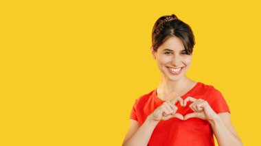 Kalp hareketi. Kırmızılı, gülümseyen kadın, romantik bir aşk işareti gösteriyor. Elleri ışık saçıyor. Mutluluk yayıyor..