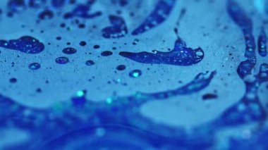 Mürekkep akışı. Banyo köpüğü dokusu. Odaklanmamış mavi renkli parlak partiküller yağlı baloncuk sıvısı emülsiyon sıvı damlama hareket soyut sanat arka planı.