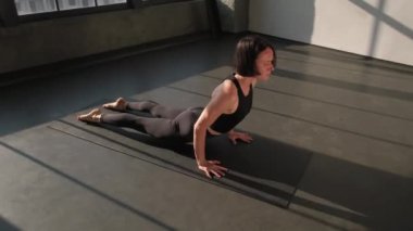 Esneme egzersizi. Yoga egzersizi. Atletik kadın spor kıyafetleri provasında aşağı doğru köpek Asana 'ya bakıyor spor paspası üzerinde beden eğitimi yapıyor kapalı spor salonundaki spor salonunda..