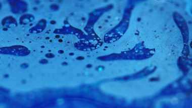 Mürekkep akışı. Banyo köpüğü dokusu. Odaklanmamış mavi renkli parlak partiküller yağlı baloncuk sıvısı emülsiyon sıvı damlalar soyut sanat arka planı.
