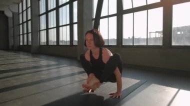 Yoga pratiği. Denge çalışması. Spor elbiseli bir kadın spor salonunda spor salonunda spor salonunda jimnastik egzersizi yaparken amuda kalkma kurbağası pozu veriyor..