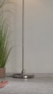 Dikey video. Meditasyon pratiği. Yoga içeride. İç huzuru. Nilüfer çiçeğinde oturan rahat, düşünceli kadın, Gyan Mudra 'ya evinde poz veriyor..