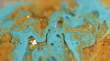 Sıvı sim dökülmüş. Parlak mürekkep. Bulanık mavi altın rengi metalik pullar kabarcıklar sıvı boya karışımı hareket soyut sanat arka planı ve bokeh ışıkları.