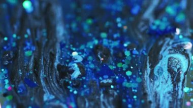 Akrilik boya karışımı. Islak sim dökülmüş. Odaklanmamış mavi renk ışıltılı pullu parçacıklar su sıvısı parlatıcı emülsiyon mürekkep damlası hareket soyut sanat arka planı.