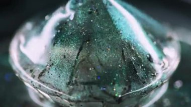 Parlak sıvı damlası. Işıldayan boya. Bulanık yeşil renkli pullu partiküller sıvı ıslak parlatıcı elmas hareketli elmas şekilli soyut sanat arkaplanı ve bokeh ışıkları.