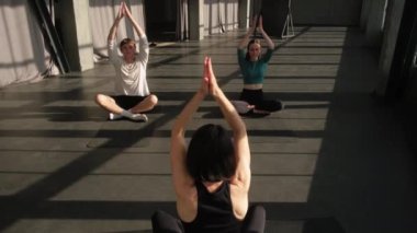Yoga dersi. Eğitim stüdyosu. Nilüfer pozisyonunda oturan kadın spor eğitmeniyle grup çalışması, spor salonundaki spor salonunda veda jesti ile son buluyor..
