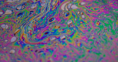 Yanardöner sıvı. Sıvı damlalar akar. Odaklanamayan mor renkli, yeşil yağlı boya eğrisi koyu siyah, aydınlık, soyut sanat arka planında akrilik kaygan..