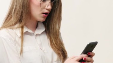 Çevrimiçi çatışma. İş iletişimi. Gözlüklü kızgın kadın beyaz boş arkaplanda izole bir şekilde telefonla mesaj yolluyor..