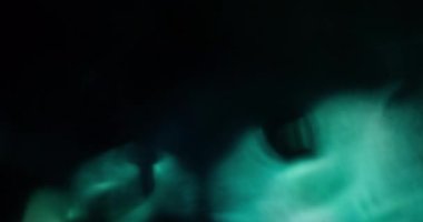 Bulanık soyut ışık. Lens fişeği. Pürüzsüz yeşil renk parıldıyor yanıp sönen parlak ışıklar modern karanlık sanat arka planında hareket ediyor..