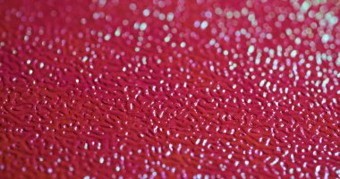 Bulanık doku. Plastik çarşaf. Kırmızı desenli yapay deri kabartması ve değiştirilmiş ışıklandırma. Dekoratif parlak cilt arkaplanı.