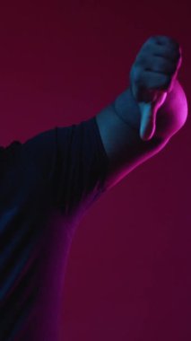 Dikey video. Nefret dolu bir jest. Olumsuz görüş. Hayal kırıklığına uğramış, kuşkucu, kuşkucu, suratında yüz ifadesi olmayan burgundy arka planında baş parmak işareti olan mutsuz bir adam..