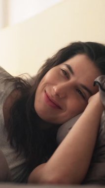 Dikey video. Huzur içinde yat. Sıcak yatak odası. Uyku zevki. Yumuşak, temiz çarşafların içinde, yorganın altında huzurlu, mutlu bir kadın..