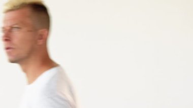 Erkek güveni. Tazelik hayranlığı. Tatmin olmuş sarışın adam, beyaz arka planda izole edilmiş gibi, yeni tarz saç kesimini onaylayarak yürüyor..