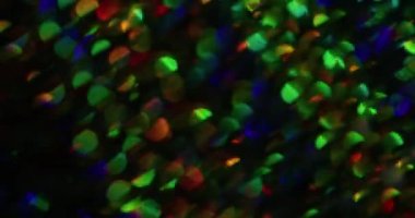 Bulanık ışık prizması. Gökkuşağı arka planı. Odaklanmamış toz sızıntısı, çok renkli yeşil ışınlar, yanıp sönen ışıltılar koyu siyah soyut sanat eserlerinde koyu renk ve bokeh efektli lens parlamaları..