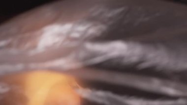 Dikey video. Gezegen kirliliği. Ekoloji problemi. Küresel ısınma Kırışık kullanılmış plastik film, dünyayı kaplıyor. Karanlıkta taze organik meyvelerle..