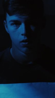 Dikey video. Gece endişesi. Korkunç bir rüyaydı. Panik atak. Dehşete kapılmış, şok olmuş bir adam gece geç saatte evinde, koyu mavi ışıkta uyandı..