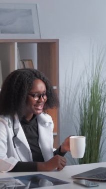 Dikey video. Sanal sağlık hizmeti. Online randevu. Teletıp çağrısı. Neşeli dost canlısı kadın pratisyen hekim hastane çalışma alanında laptopta tıbbi toplantıya danışmanlık yapıyor..