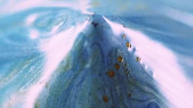 Parıldayan sıvı dökülüyor. Parlak boya dökülmüş. Bulanık mavi, altın beyazı, ışıldayan parçacıklar, desen, mürekkep, soyut sanat arka planı..