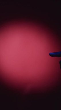 Dikey video. İnsan dayanışması. Etnik eşitlik. Çoklu kültürel çeşitlilik. Erkek ve kadın parmaklarını kırmızı spot ışığı arkaplanındaki yaratıcı reklama dokunduruyor..