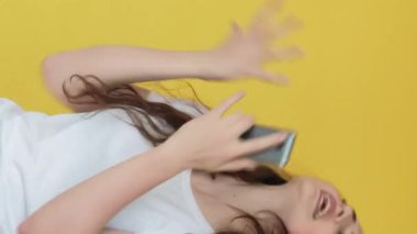 Dikey video. Mobil çatışma. Kızgın bir konuşma. İletişim sorunu. Sinirli bir kadın bağırıyor telefonda konuşuyor, sarıda izole edilmiş..