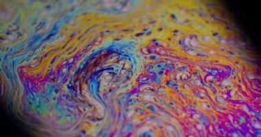 Boya damlacıkları. Yağlı gökkuşağı. Odaklanmamış mor yeşil sıvı boya eğrisi koyu siyah bulanık ışık soyut sanat arka planında akrilik kaygan.