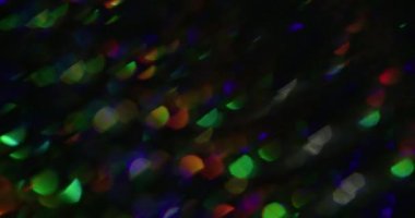 Işıltılı arka plan. Gökkuşağı efektini üstüste koy. Odaklanamayan toz sızıntısı, çok renkli yeşil ışınlar, yanıp sönen ışıltılar, koyu siyah, soyut sanat eserleri üzerinde parıldıyor..