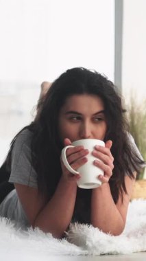 Dikey video. Sabah kahvesi. Hafta sonu istirahati. Rahatlamış, mutlu, hayalperest kadın, yeni günün tadını çıkarıyor..