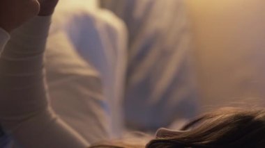 Dikey video. Gece çevrimiçi oyunu. Çocuk eğlencesi. Uyku zamanı eğlencesi. Küçük kız yatmadan önce cep telefonuyla oynuyor. Karanlık bir yatak odasında, sıcak bir lambayla..