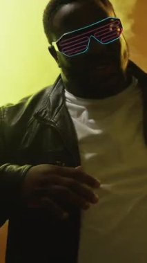 Dikey video. Rap performansı. 90 'ların partisi. Gece kulübü etkinliği. Havalı, kendine güvenen, fütürist güneş gözlüklü, dumanlı, neon ışıklı sahnede hip hop şarkısı söyleyen bir adam..