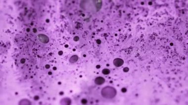 Yağlı sıvı dalgası. Boya dökülmüş. Bulanık mor köpüklü köpük mürekkep emülsiyonu parlak gümüş parçacıklar soyut arkaplan akışını harmanlıyor.