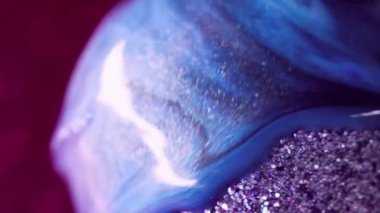 Köpüklü sıvı dökülmüş. Pırıl pırıl. Pembe soyut arkaplan üzerine ışıldayan kürenin üzerine parlayan parlak mavi mor renk parçacıkları desen mürekkebi dökülüyor.