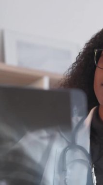 Dikey video. Doktor uzmanlığı. Radyoloji uzmanı. Hastane sağlık hizmetleri. Klinikte teşhis tedavisi için röntgeni inceleyen odaklanmış zeki kadın doktor..