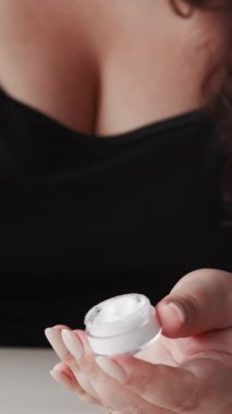 Dikey video. Cilt nemlendirici. Yüz bakımı. Yaşlanma karşıtı tedavi. Kilolu obez kadın besleyici yüz kremi sürerek vücut losyonu sürüyor..