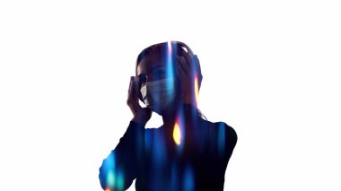 Karantina müziği. Kulağa hoş geliyor. Yüz maskeli bir kadının silueti, beyaz boş arkaplanda bulanık ışıklarda kulaklıkla rahatlatıcı sesleri dinlemekten zevk alıyor..