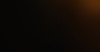 Odaklanamayan parıltı. Işık sızıntısı. Sarı turuncu parlak kıvılcım kıvılcımları koyu bulanık modern arka planda bokeh etkisi ile hareket ediyor.