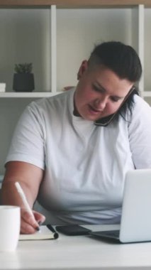 Dikey video. Çoklu görev. Meşgul sekreter. Yorulmak bilmeyen aşırı kilolu bir kadın zor bir işi yönetiyor iş atamaları yapıyor telefonda notlar alıyor..