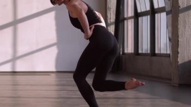 Sağlıklı bir vücut. Denge egzersizi. Spor kıyafetlerindeki atletik kadın spor yogası spor salonu stüdyosunun içinde kas esneme hareketleri yapıyor..