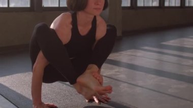 Vücut gerilmesi. Denge çalışması. Spor elbiseli bir kadın spor salonunda spor salonunda spor salonunda jimnastik egzersizi yaparken amuda kalkma kurbağası pozu veriyor..