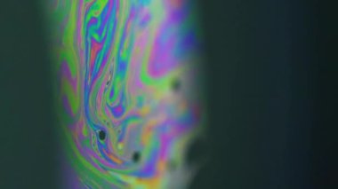 Dikey video. Psikedelik mürekkep. Gökkuşağı sıvısı. Siyah soyut sanat arkaplan üzerinde eğri içinde çözünmüş renk yağ kabarcığı asit sıvı karıştırma hareketi.