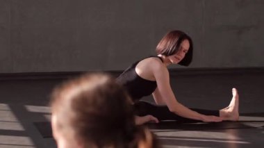 Fiziksel antrenman. Pilates egzersizi. Grup üyeleri spor salonundaki spor minderi üzerindeki kadın yoga eğitmeninden sonra jimnastik sınıfı egzersizlerini tekrarlıyor..