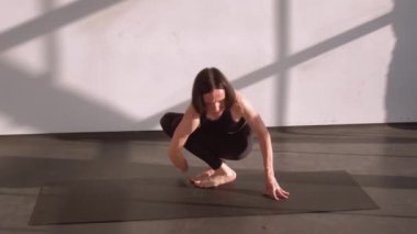 Sağlıklı spor. Denge yogası. Aktif giyim ve amuda kalkma egzersizi yapan atletik bir kadın stüdyo içinde spor paspası üzerinde asana pozu veriyor..