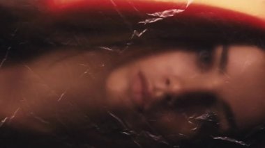 Dikey video. Kötü bir his. Etkisiz hale getirilmiş portre. Endişeli kadın soluyor kırışık dokusu kırmızı turuncu parlaklıkta polietilen film odak dışı.
