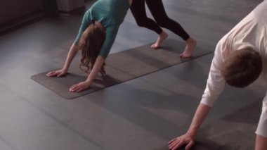 Antrenman yapıyorum. Yoga asana. Grup üyeleri denge egzersizi yapıyor köpek pozisyonuna bakıyor kadın fitness hocası içeride spor salonunda minder üzerinde kas geriyor..