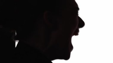 Çığlık atan siluet. Zihinsel bozukluk. Sinir krizi. Duygusal bir kriz. Beyazların arka planında izole bir şekilde bağıran, hayal kırıklığına uğramış bir kadının koyu renk kontrast profili.