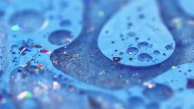 Işıldayan emülsiyon. Parlak yağ kabarcıkları. Odaklanmamış mavi renkli ışıldayan parçacıklar jel damlaları akrilik boya sıvısı parlatıcı doku akış hareketi soyut sanat arka planı.