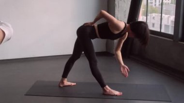 Fiziksel antrenman. Yoga seansı. Bayan fitness eğitmeni, beden egzersizleri, kapalı spor salonundaki Asya duruşunun düzeltilmesine yardımcı oluyor..