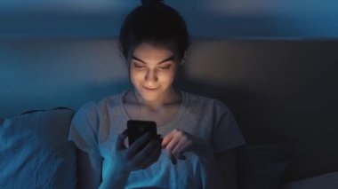 Gadget gecesi. İnternet bağımlılığı. İnternette uykusuzluk. Karanlık yatak odasında geç saatte cep telefonunu kullanan meraklı kız..