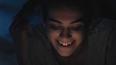 Gece sohbeti. Geç iletişim. Çevrimiçi boş zaman. Mutlu şakacı kadın mesajlaşır mesajlaşır. Karanlık odada cep telefonuyla flört eder..