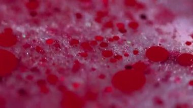 Köpüklü köpükler. Parıltılı boya karışımı. Bulanık kırmızı renk parlak pullu parçacıklar mürekkep damlaları şeffaf jel sıvısı sızıntısı soyut sanat arka planı ve bokeh ışıkları.